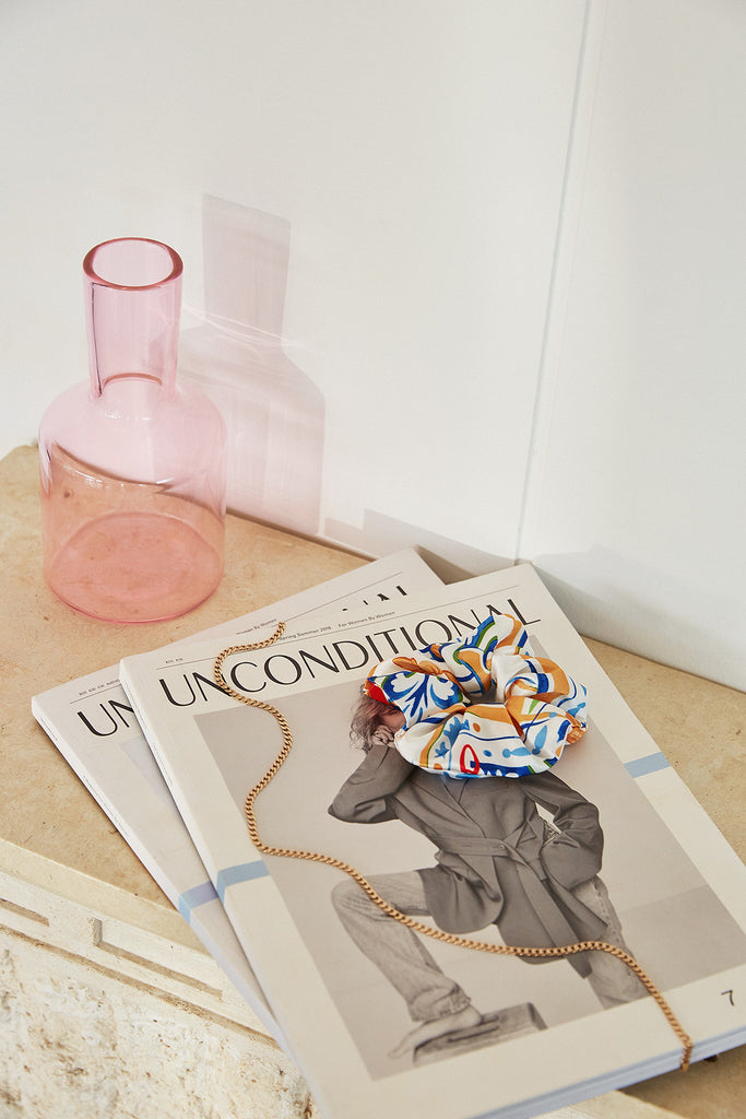 The Bella Descanso Palazzo Scrunchies displayed on golden house light on a stone plinth alongside Unconditional magazine, delicate gold jewellery & the Maison Balzac J'ai Soif Carafe. Luxury scrunchies are the perfect accessory for hairstyle inspo.